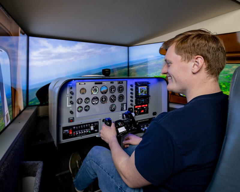 Male aviation student using flight simulator at aerospace campus.